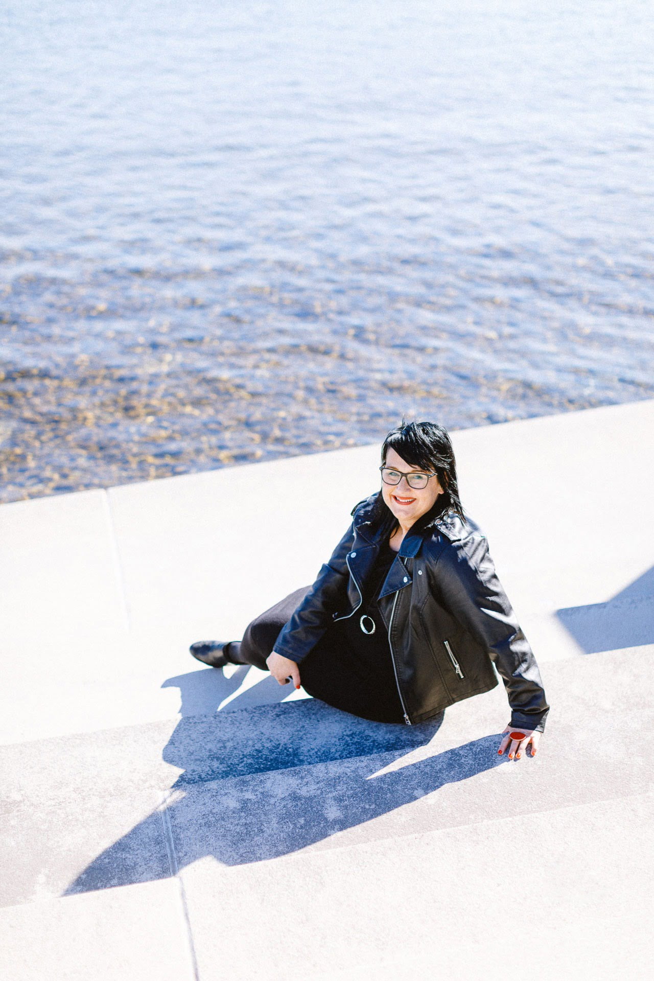 Sabine sitzt am Bodensee nahe Friedrichshafen und schaut in die Kamera.