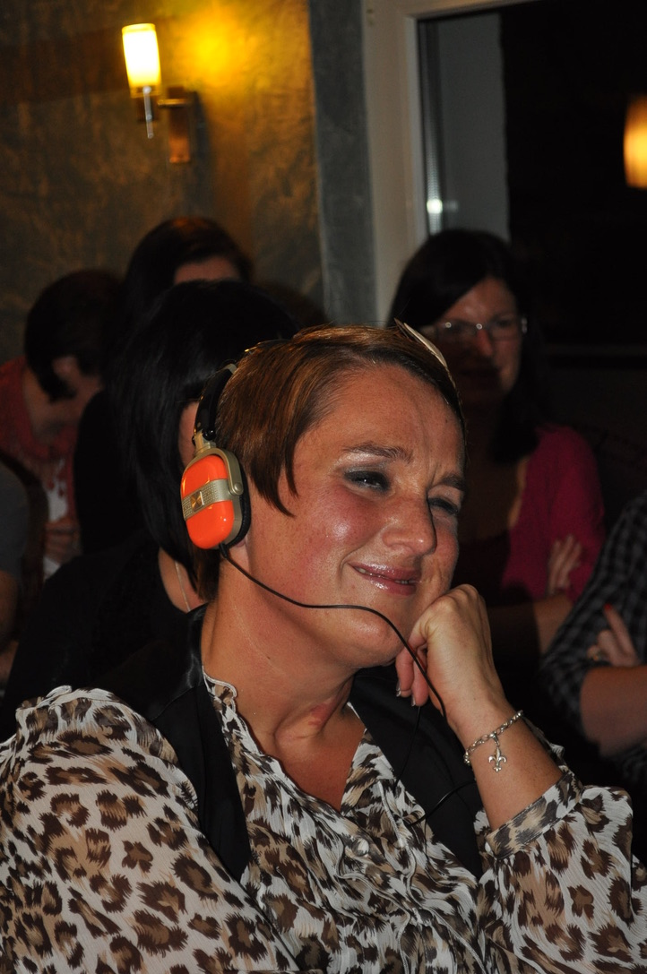 Sabine hört mit Kopfhörern einen Podcast aus ihren Empfehlungen und lässt sich für ihre Arbeit inspirieren.