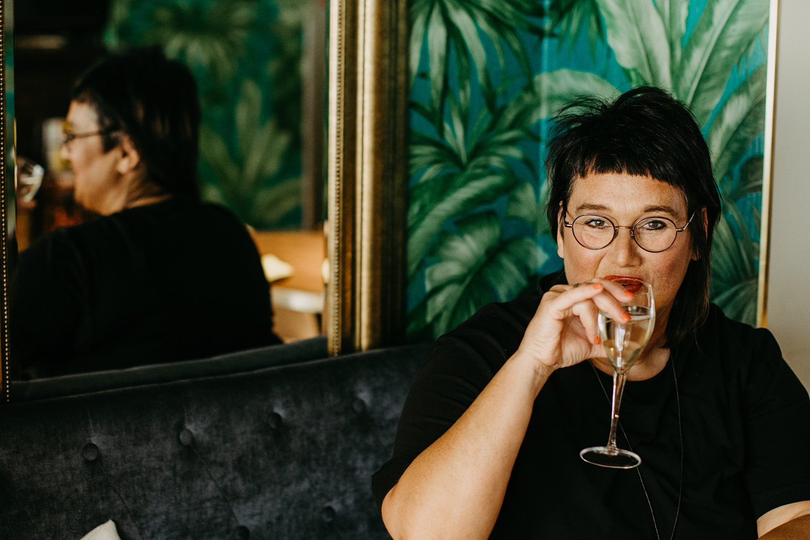 Sabine Coach für Frauen ab 50. Sabine, Coach für Frauen ab 50, trinkt in einem Cafe ein Glas Sekt.