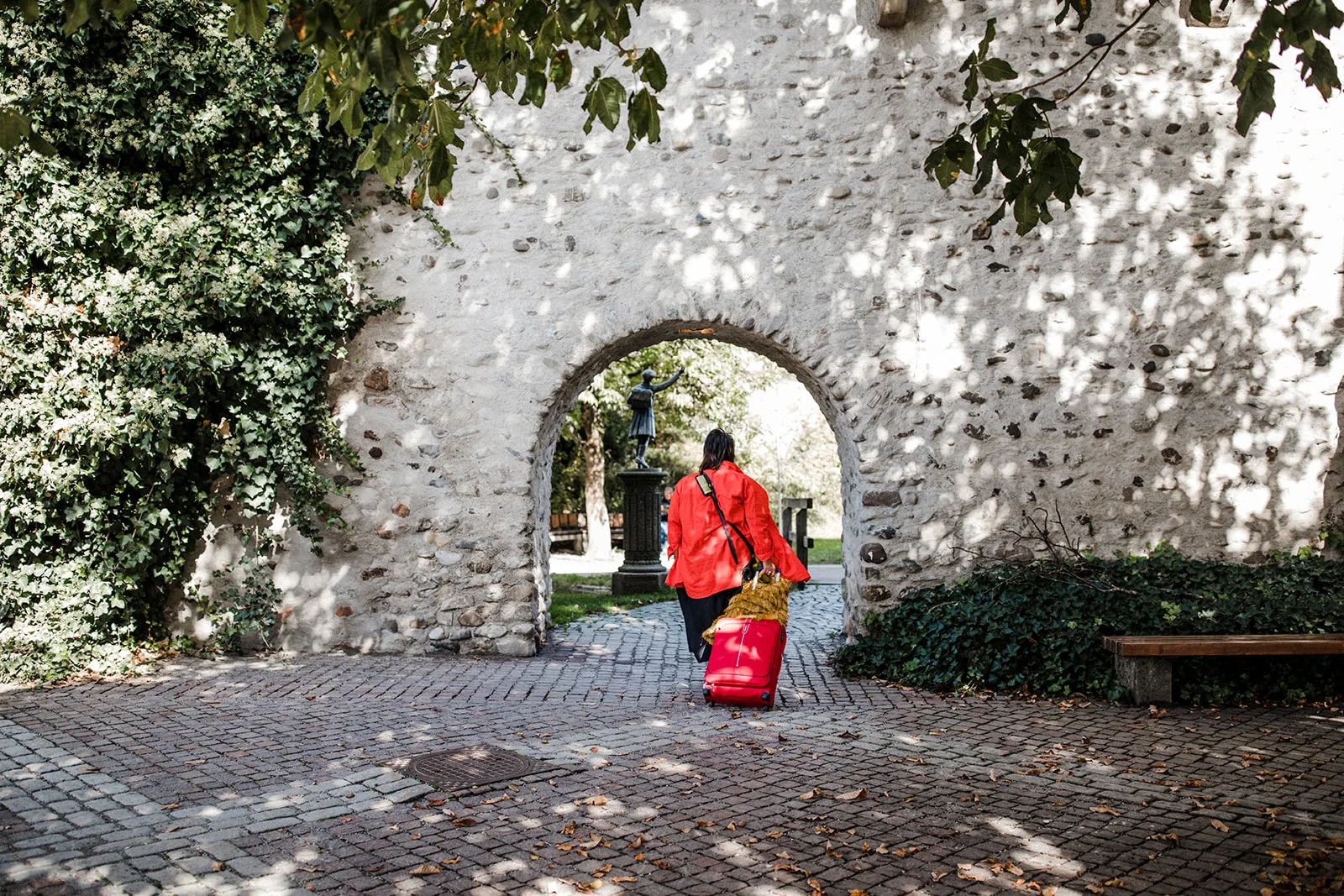 Sabine im Coaching für Frauen ab 50 geht mit einem roten Koffer durch ein Tor.