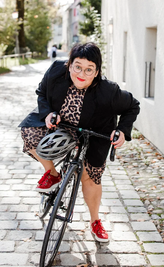 Sabine, Speakerin für Frauen, sitzt auf einem Rennrad und schaut in die Kamera.